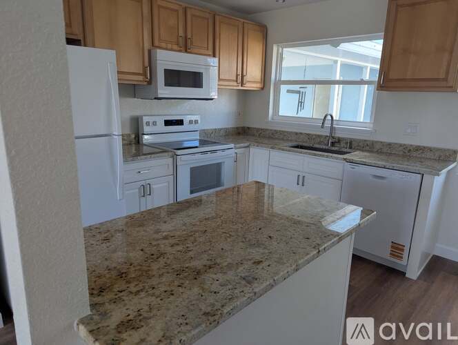 A kitchen with granite countertops and white appliances.