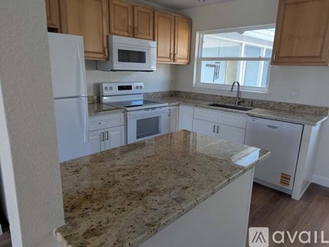 A kitchen with granite countertops and white appliances.