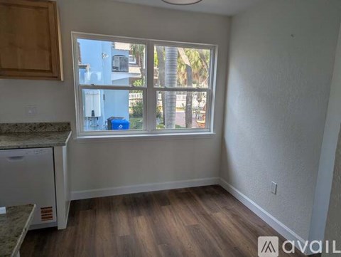 A room with a window showing a view of a street with palm trees.