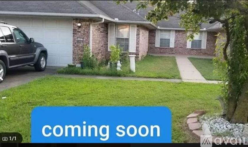 A car is parked in front of a house with a "coming soon" sign.