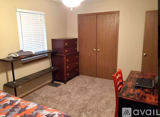 A bedroom with a bed, desk, and chair.