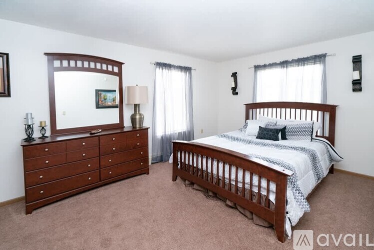 A bedroom with a bed, dresser, and mirror.