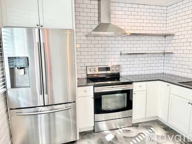 A kitchen with a stainless steel refrigerator and white cabinets.