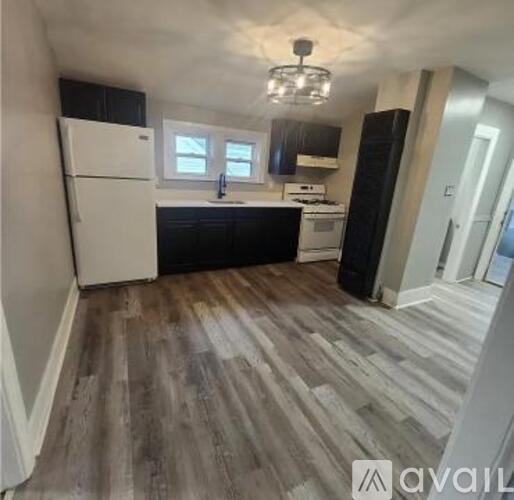 A kitchen with a white refrigerator and black cabinets.