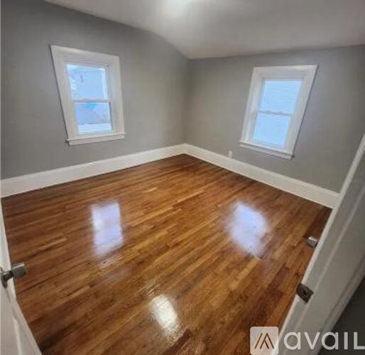 A room with wooden floors and two windows.