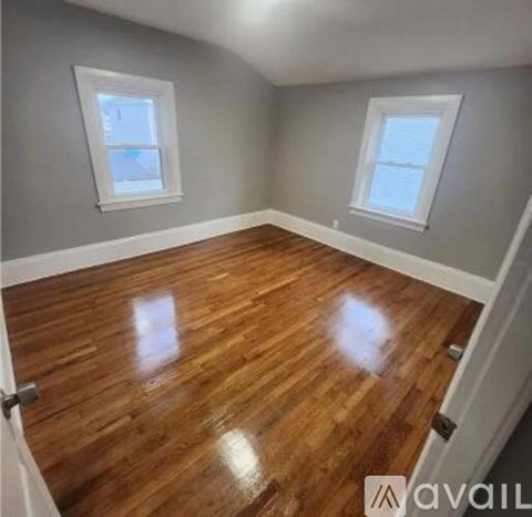 A room with wooden floors and two windows.