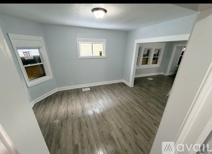 A room with wooden flooring and a window with blinds.