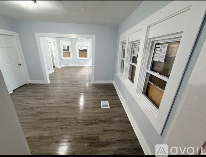 A long, empty hallway with wood floors and white walls.