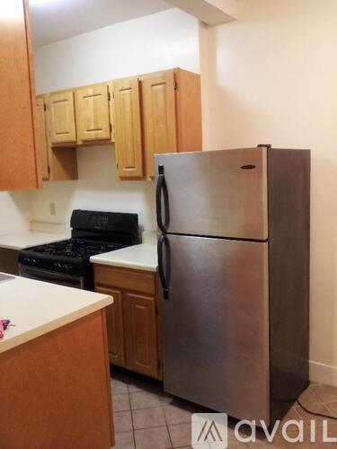 A kitchen with a stainless steel refrigerator and wooden cabinets.