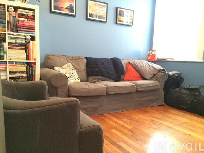 A living room with a grey couch and a bookshelf filled with books.