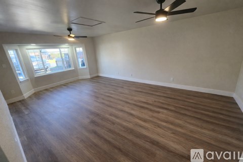 A room with a ceiling fan and wooden flooring.