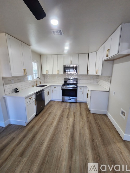 A kitchen with white cabinets and wooden floors.