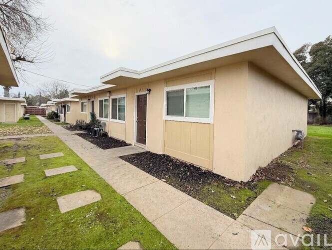 A beige house with a brown door and a window is for sale.