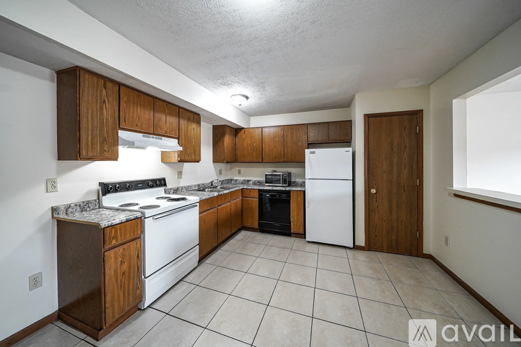 A kitchen with white appliances and wooden cabinets.