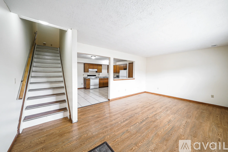 A room with wooden floors and a staircase leading to another room.