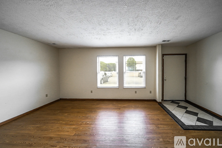 A room with wooden floors and a checkered rug in front of a door.