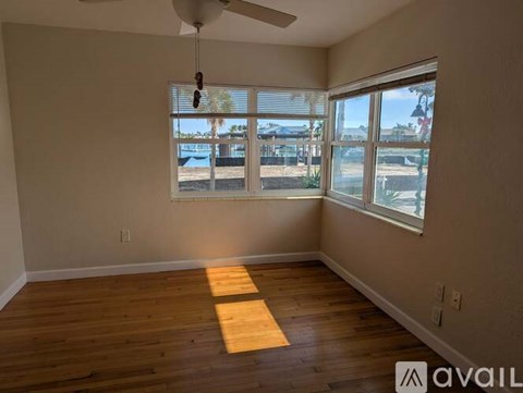 A room with wooden flooring and a window overlooking a fenced area.