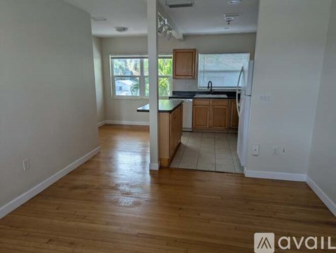 A kitchen area with wooden floors and cabinets.