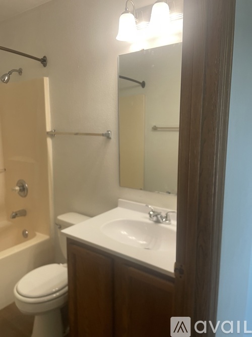 A bathroom with a toilet, sink, and mirror.