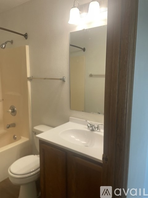 A bathroom with a toilet, sink, and mirror.