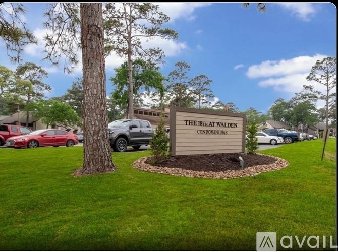A sign for The Bridle Walk Condominiums is surrounded by grass and trees.