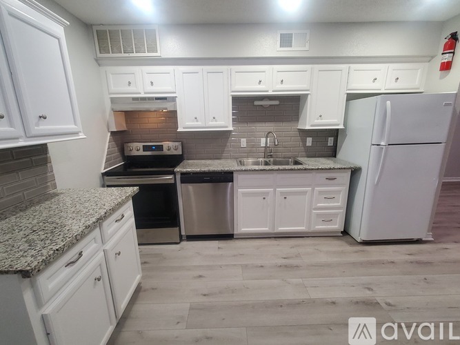 A kitchen with white cabinets and a granite countertop.