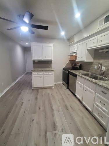 A kitchen with white cabinets and a wooden floor.