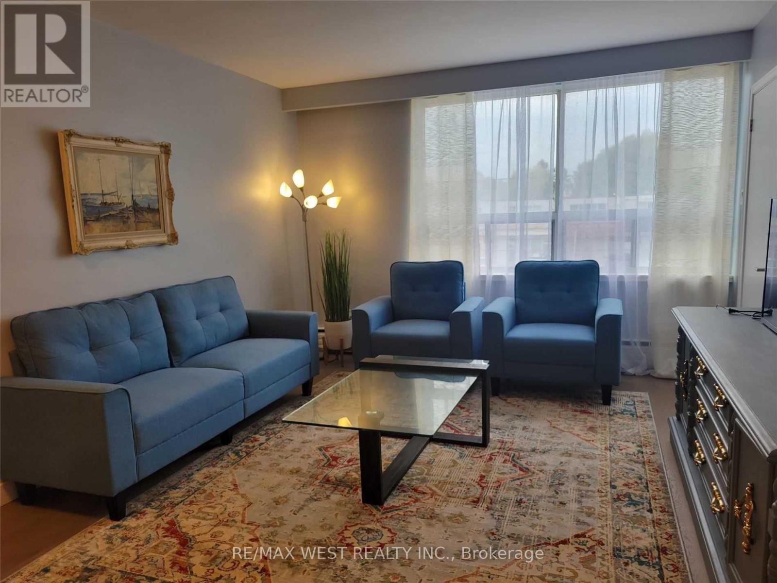 A living room with a blue couch, two chairs, and a coffee table.