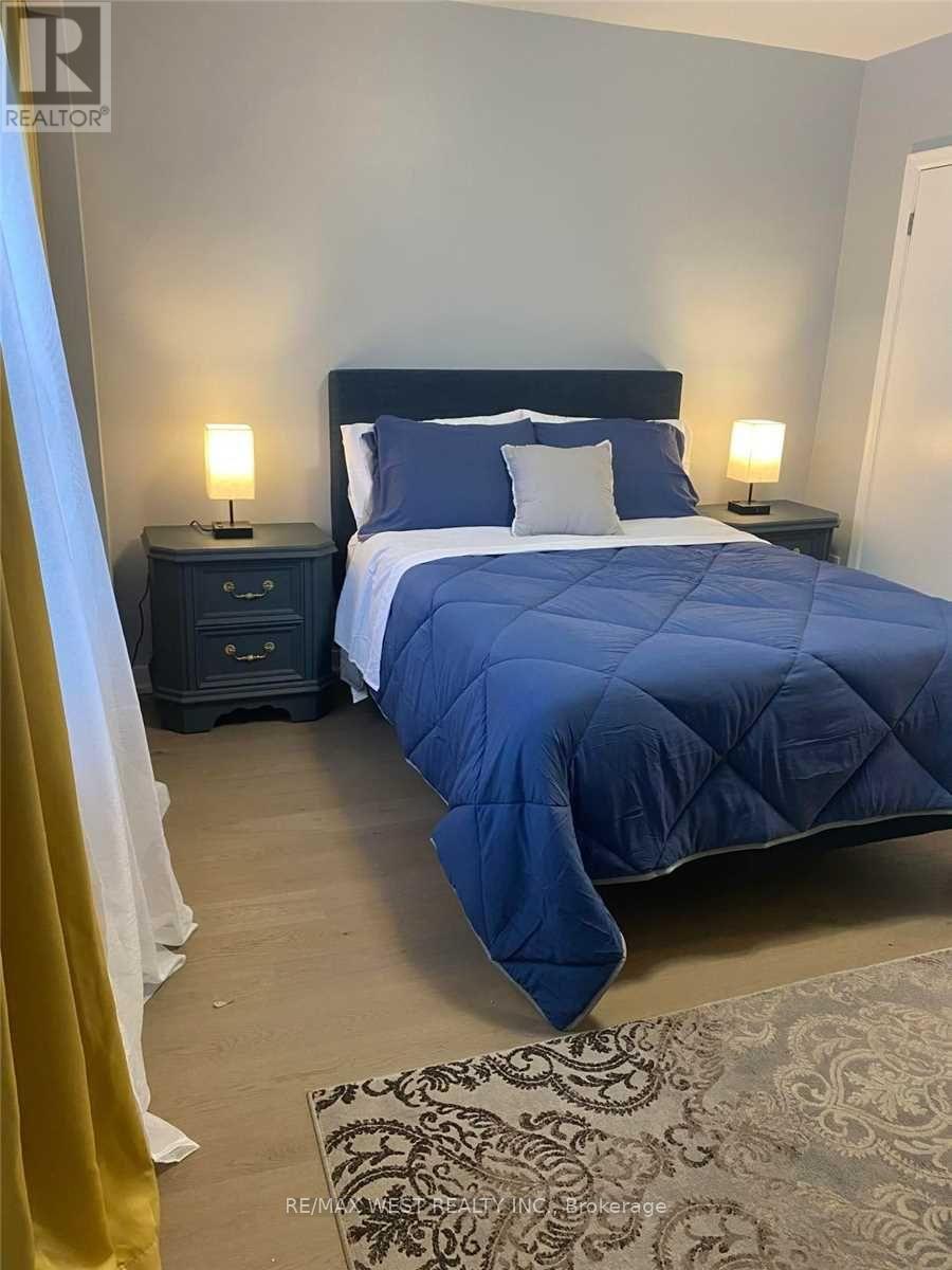 A bedroom with a large bed and two lamps.