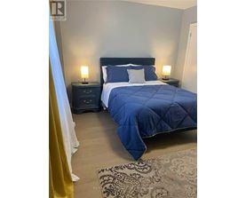 A bedroom with a large bed and two lamps.