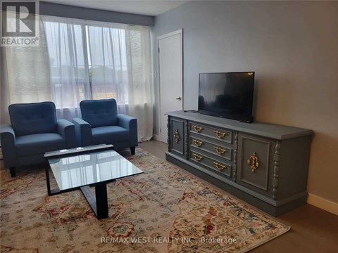 A living room with a grey cabinet, a glass table and two blue chairs.