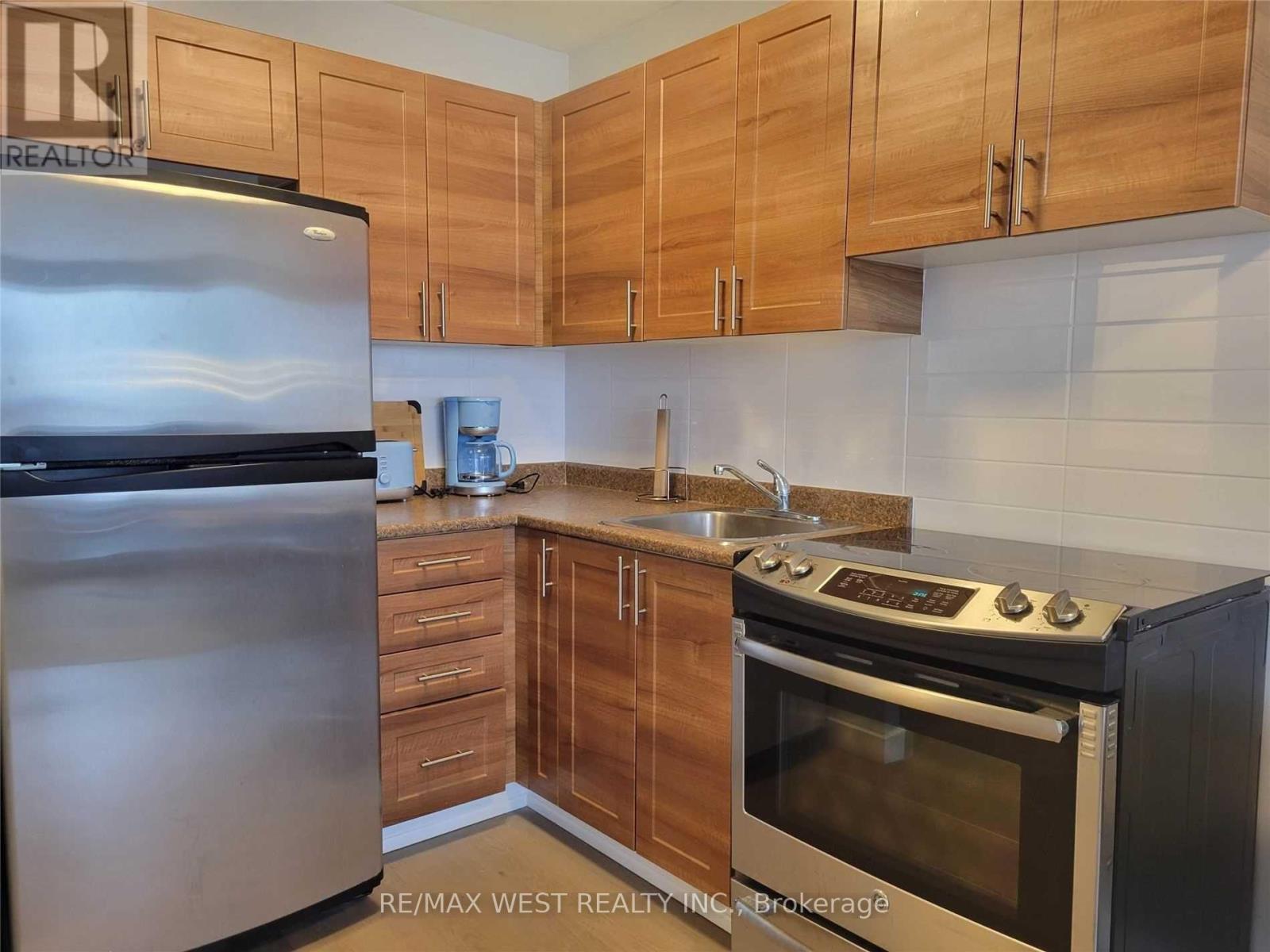 A kitchen with wooden cabinets and a stainless steel refrigerator.