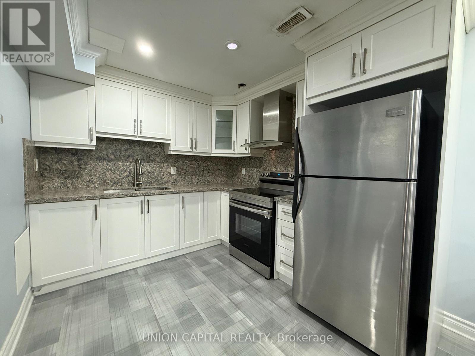 A kitchen with a stainless steel refrigerator and white cabinets.