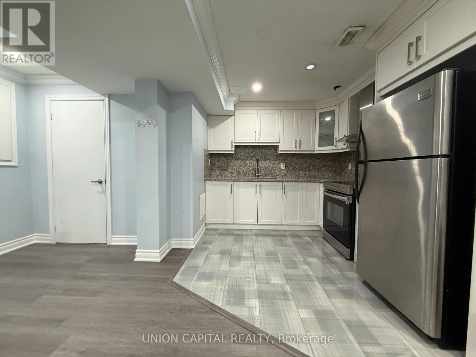 A kitchen with a stainless steel refrigerator and a checkered floor.