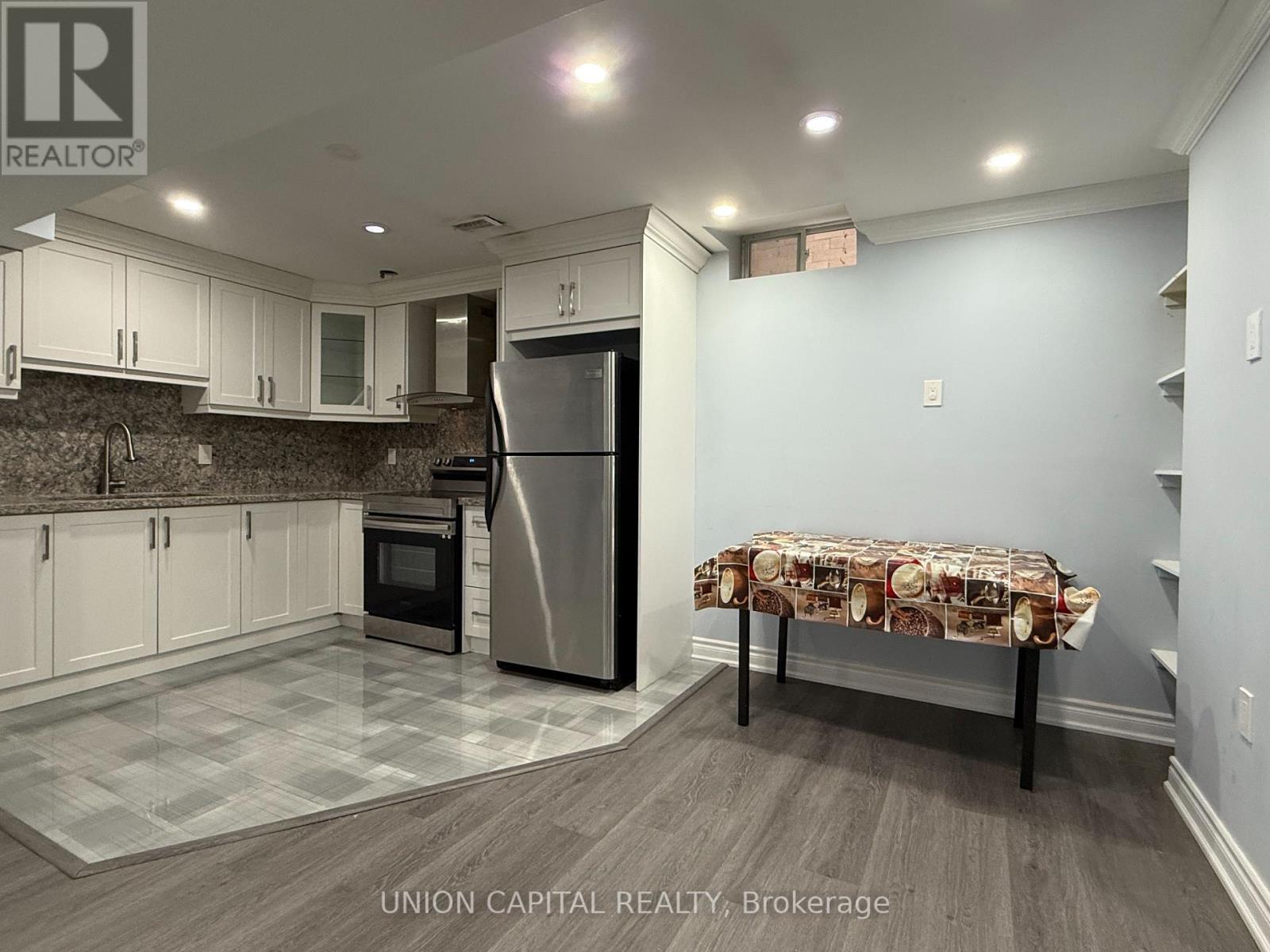 A kitchen with a refrigerator, oven, and cabinets.