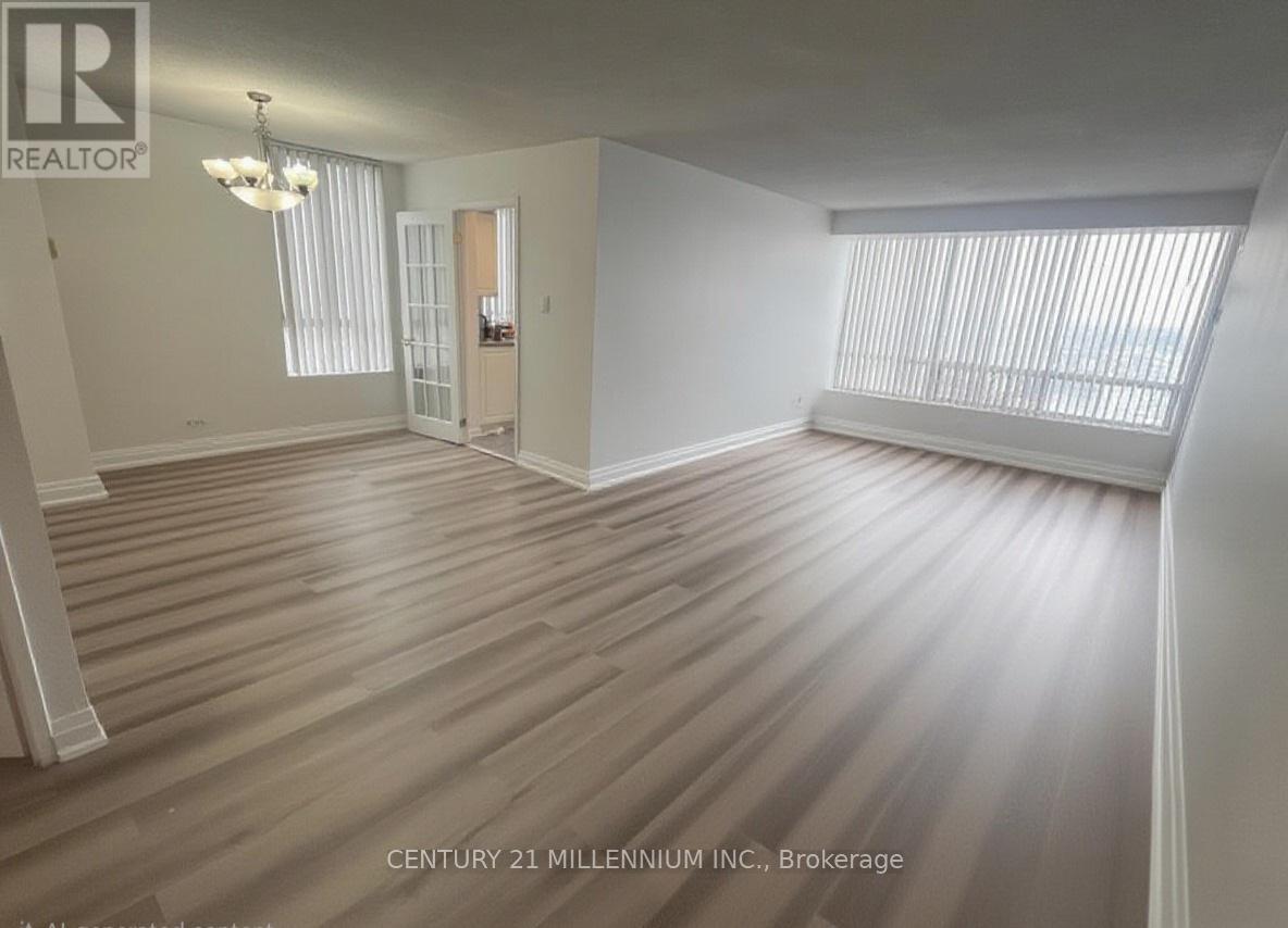 A spacious room with wooden flooring and a chandelier.