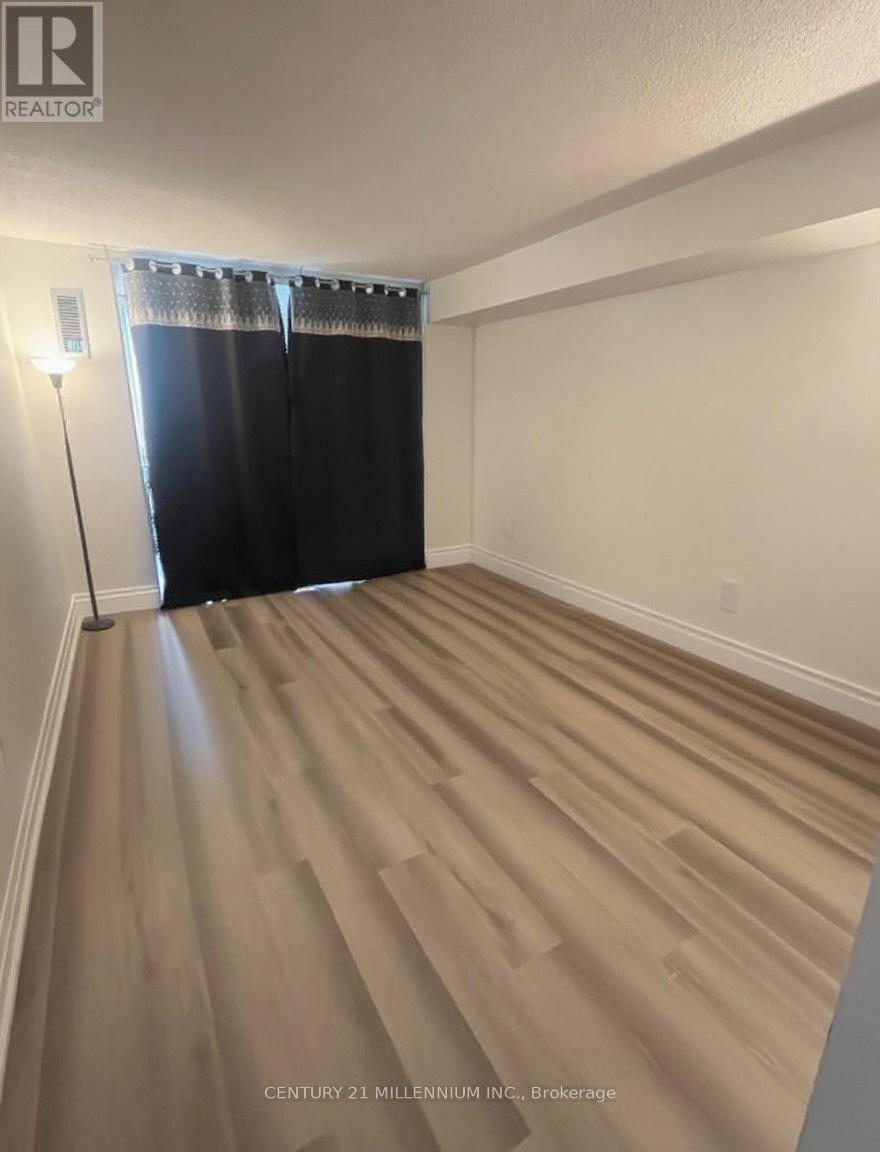 A room with wooden flooring and a window with black curtains.