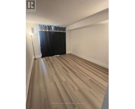 A room with wooden flooring and a window with black curtains.