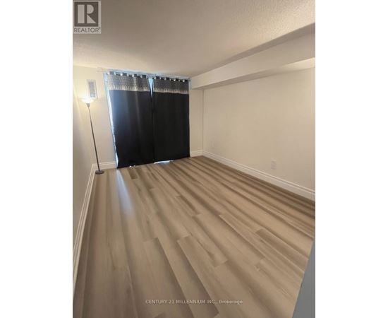 A room with wooden flooring and a window with black curtains.