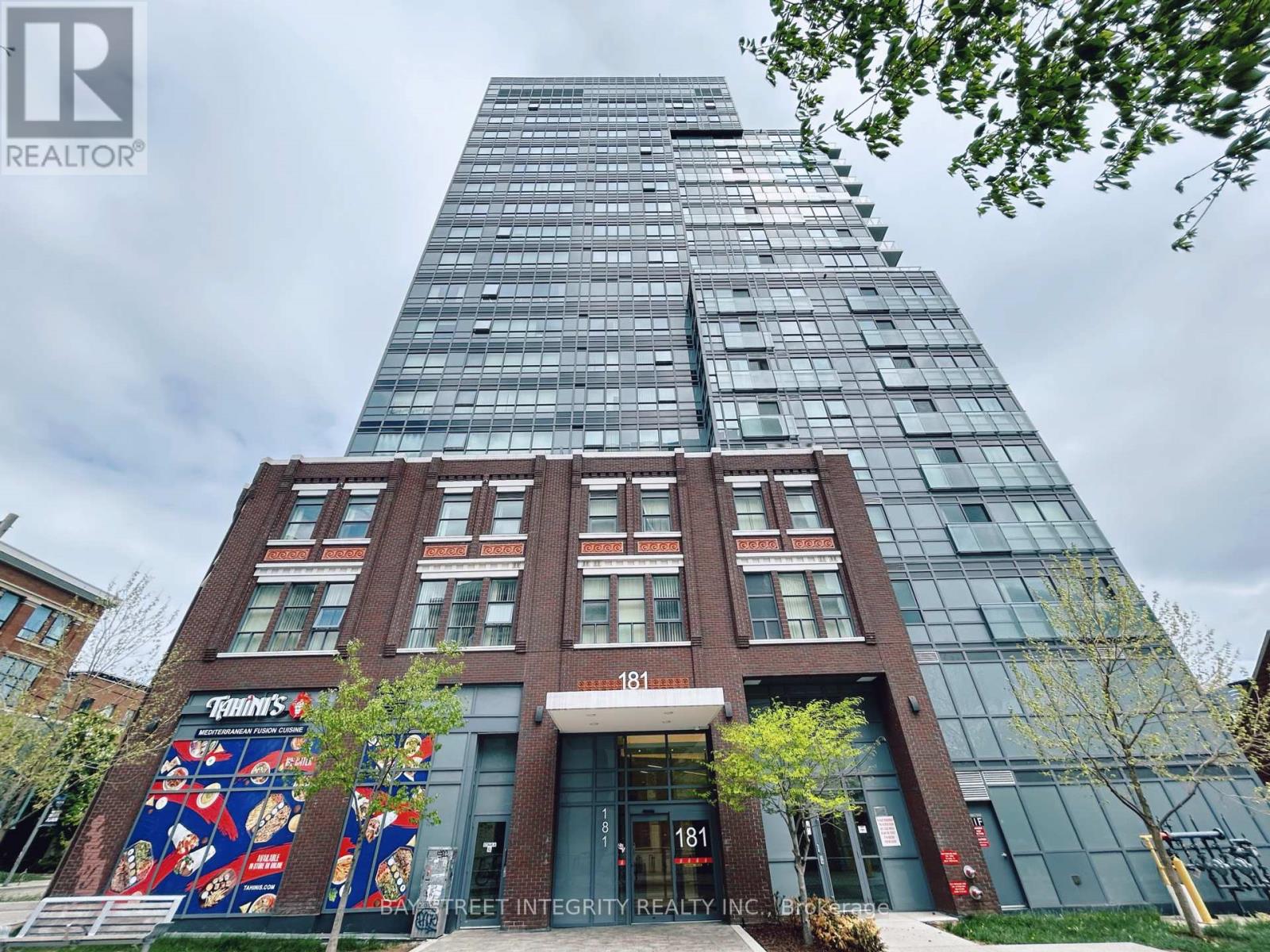 A tall building with a glass facade and a red brick base with a sign that reads 181.