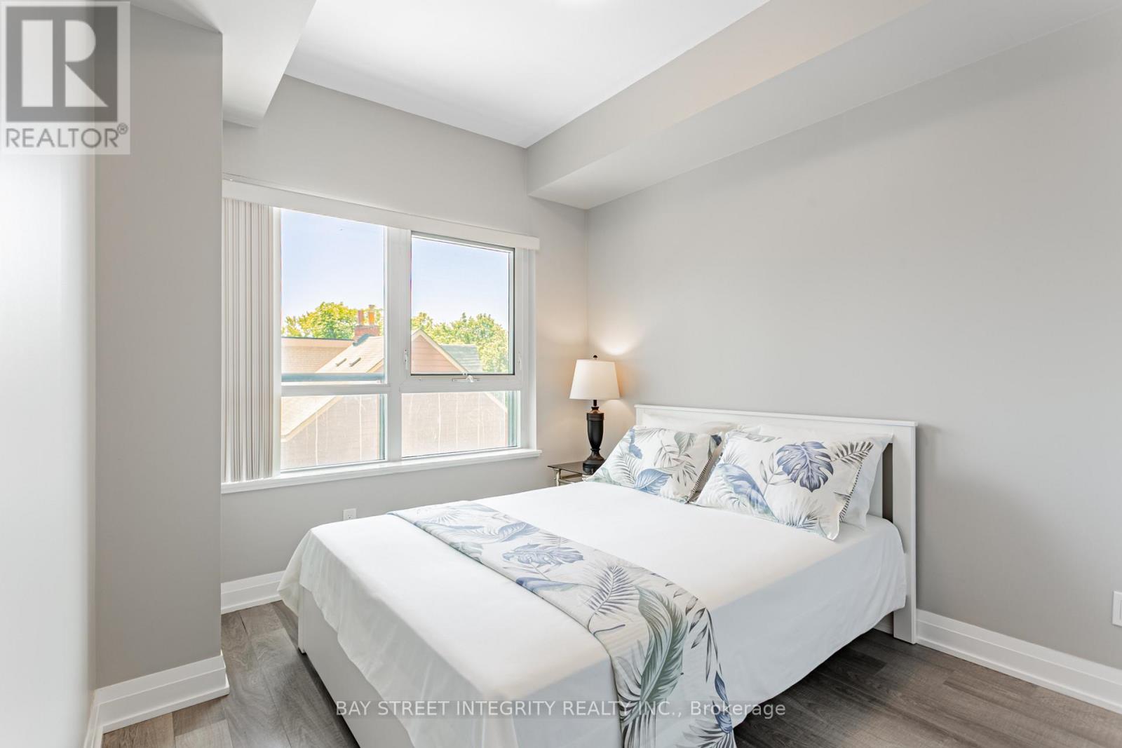 A bedroom with a large bed and a window overlooking a residential area.