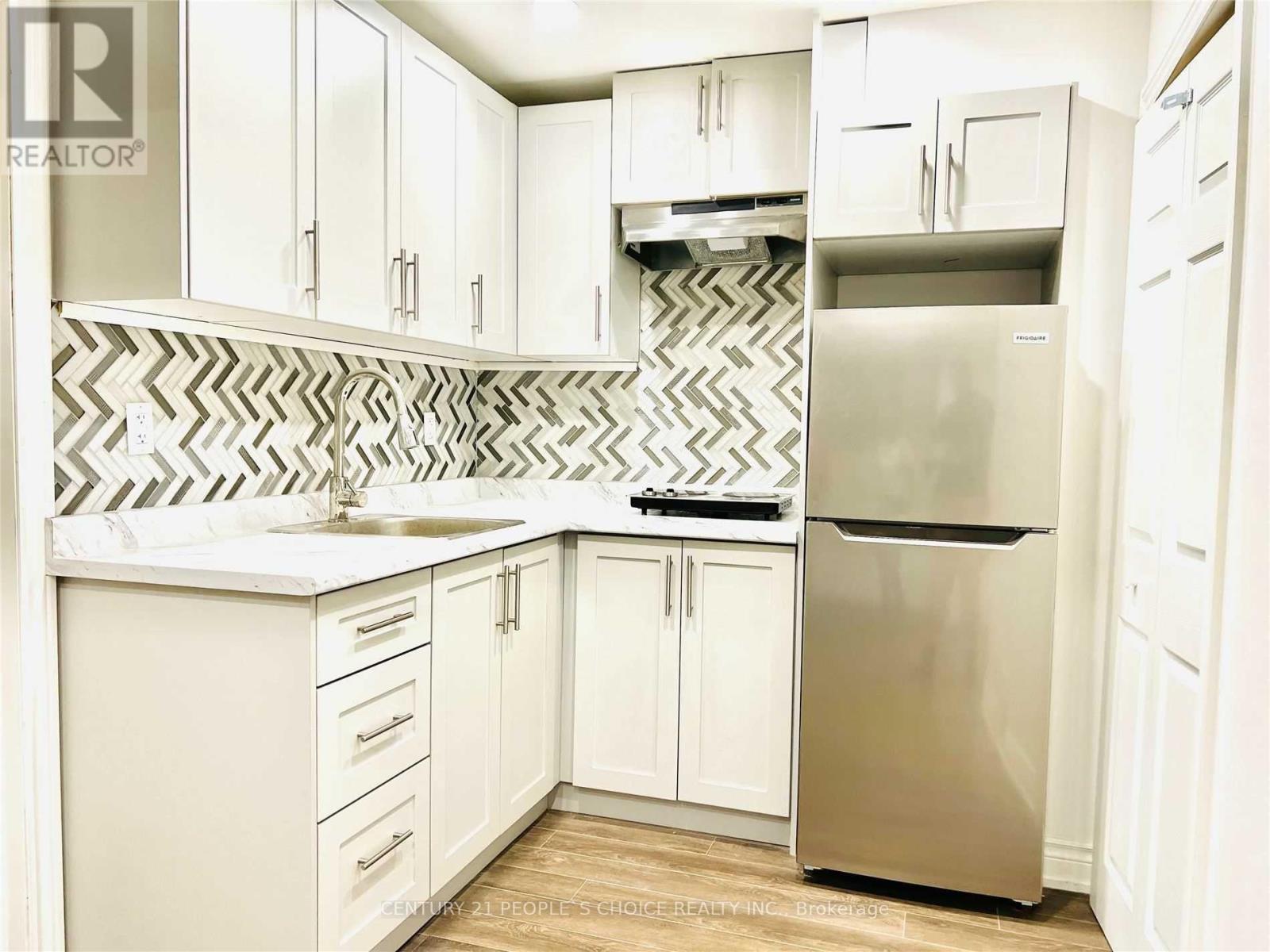 A kitchen with white cabinets and a stainless steel refrigerator.