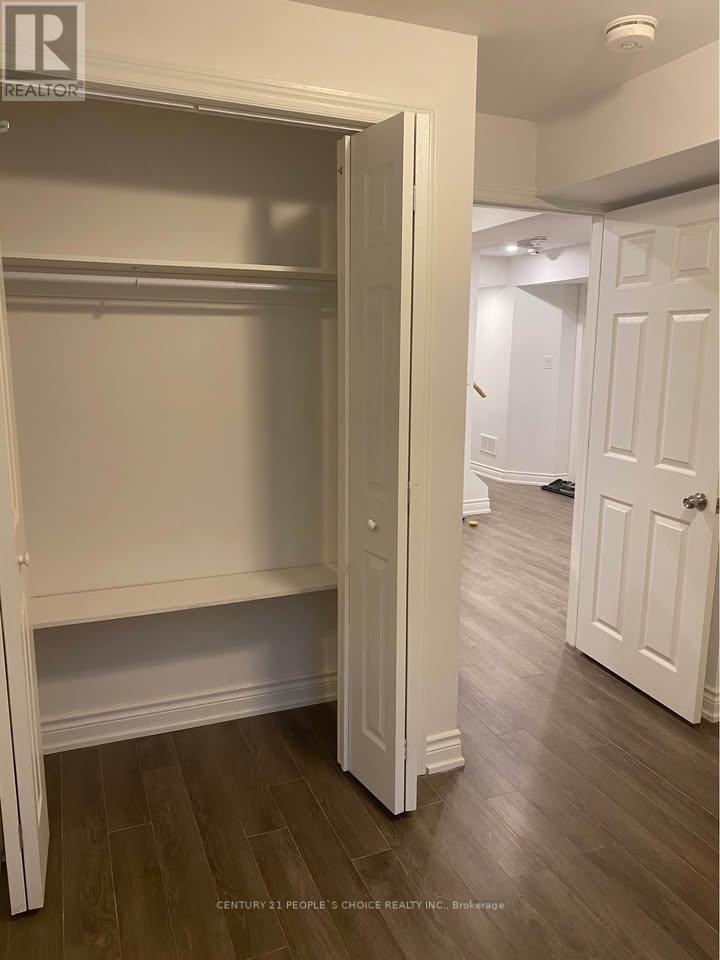 A white closet with a door open is in a room with wood floors.