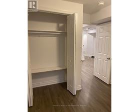 A white closet with a door open is in a room with wood floors.