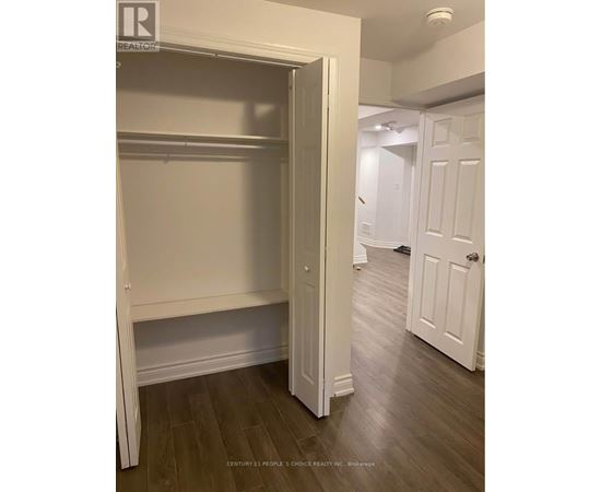 A white closet with a door open is in a room with wood floors.
