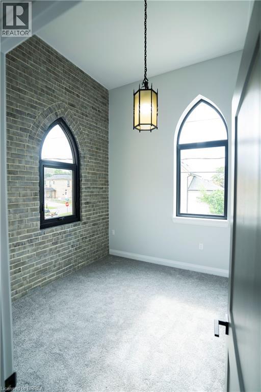 A room with a brick wall and two arched windows.