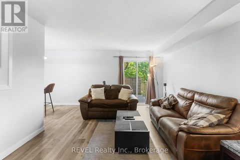 A living room with a brown leather couch and a wooden floor.