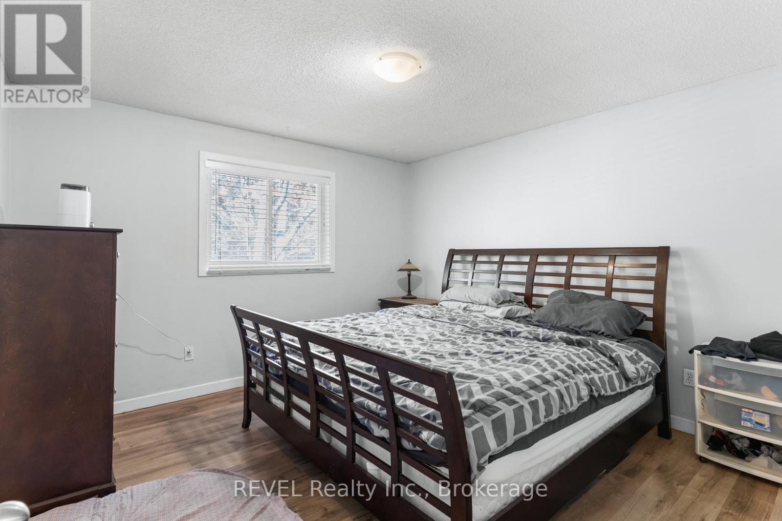 A bedroom with a bed, nightstand, and window.