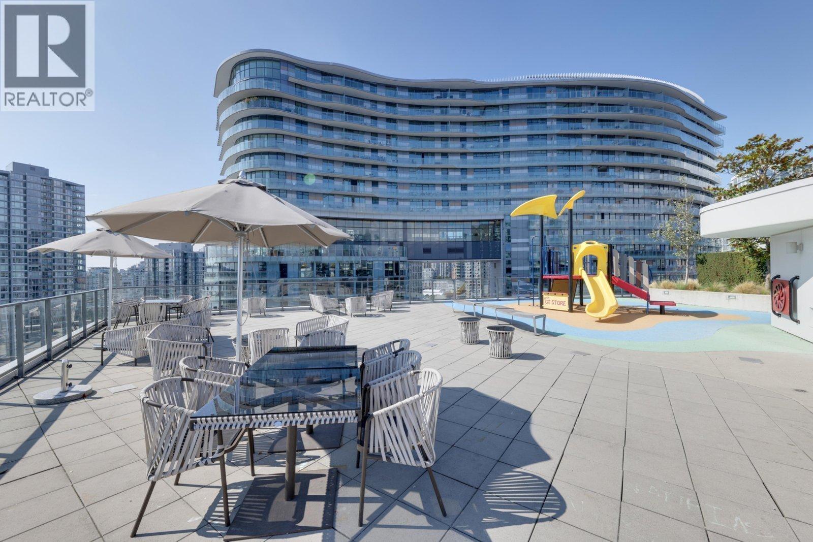 A modern building with a glass facade and a playground in front.