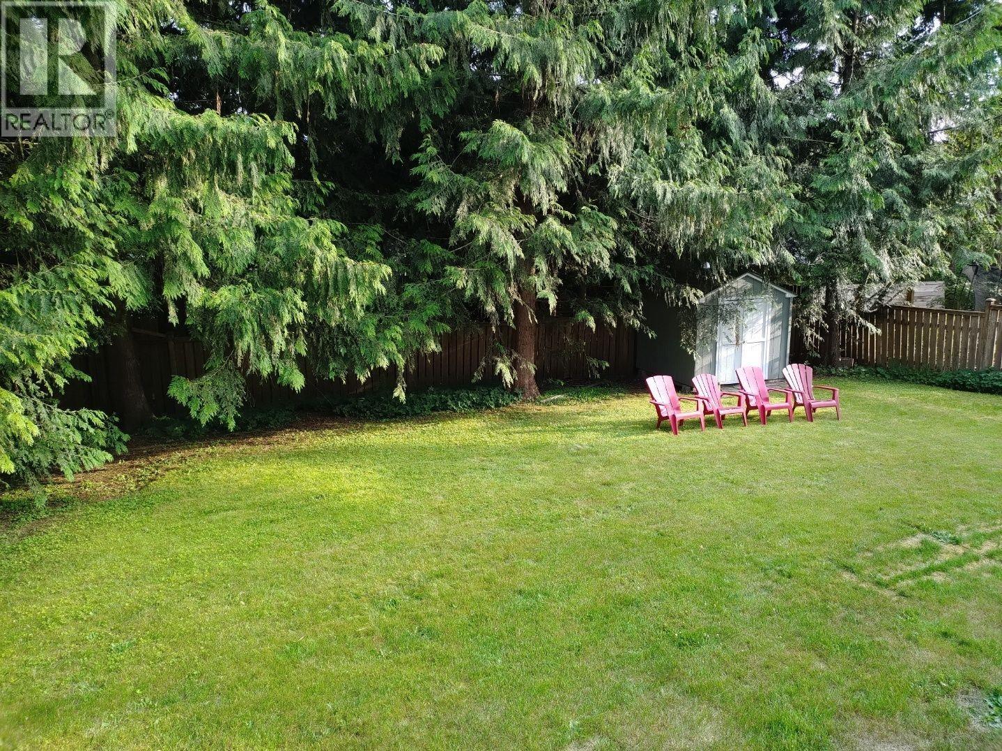 A backyard with a lawn, trees, and a patio table.